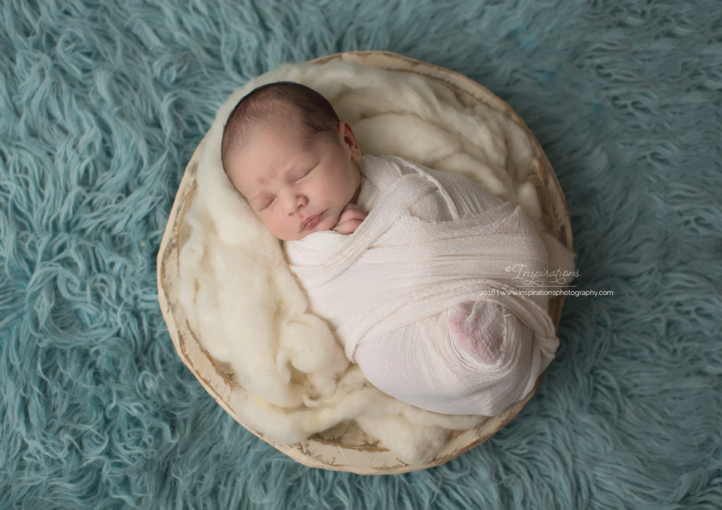 newborn baby sleeping in blanket in basket