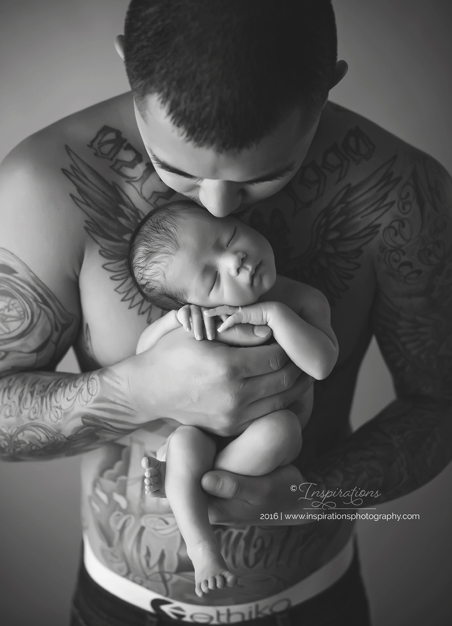 dad with tattoos cuddles newborn