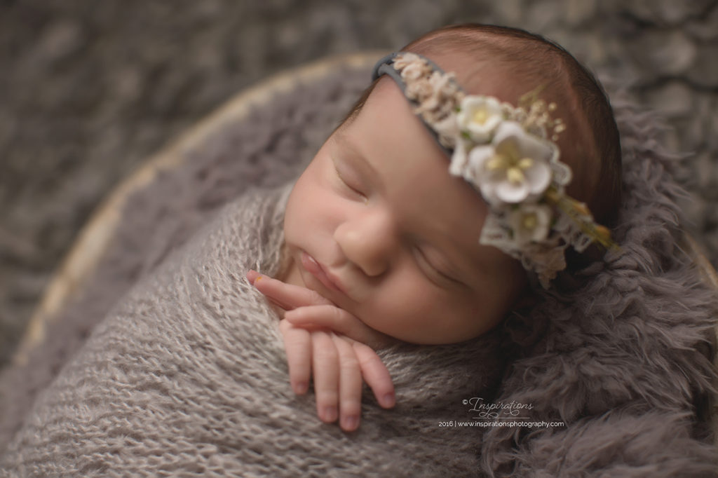 Newborn baby girl sleeping in grey blanket