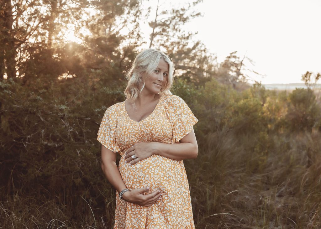 maternity photography of mom holding belly in yellow dress