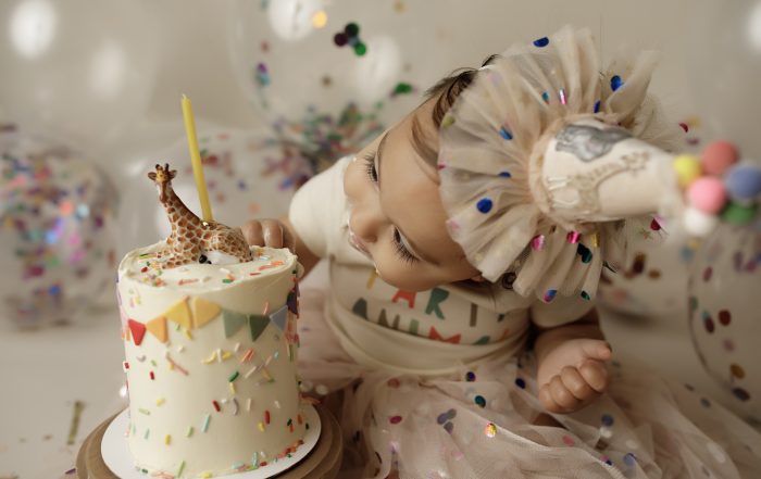 first birthday cake smash session with baby looking at cake