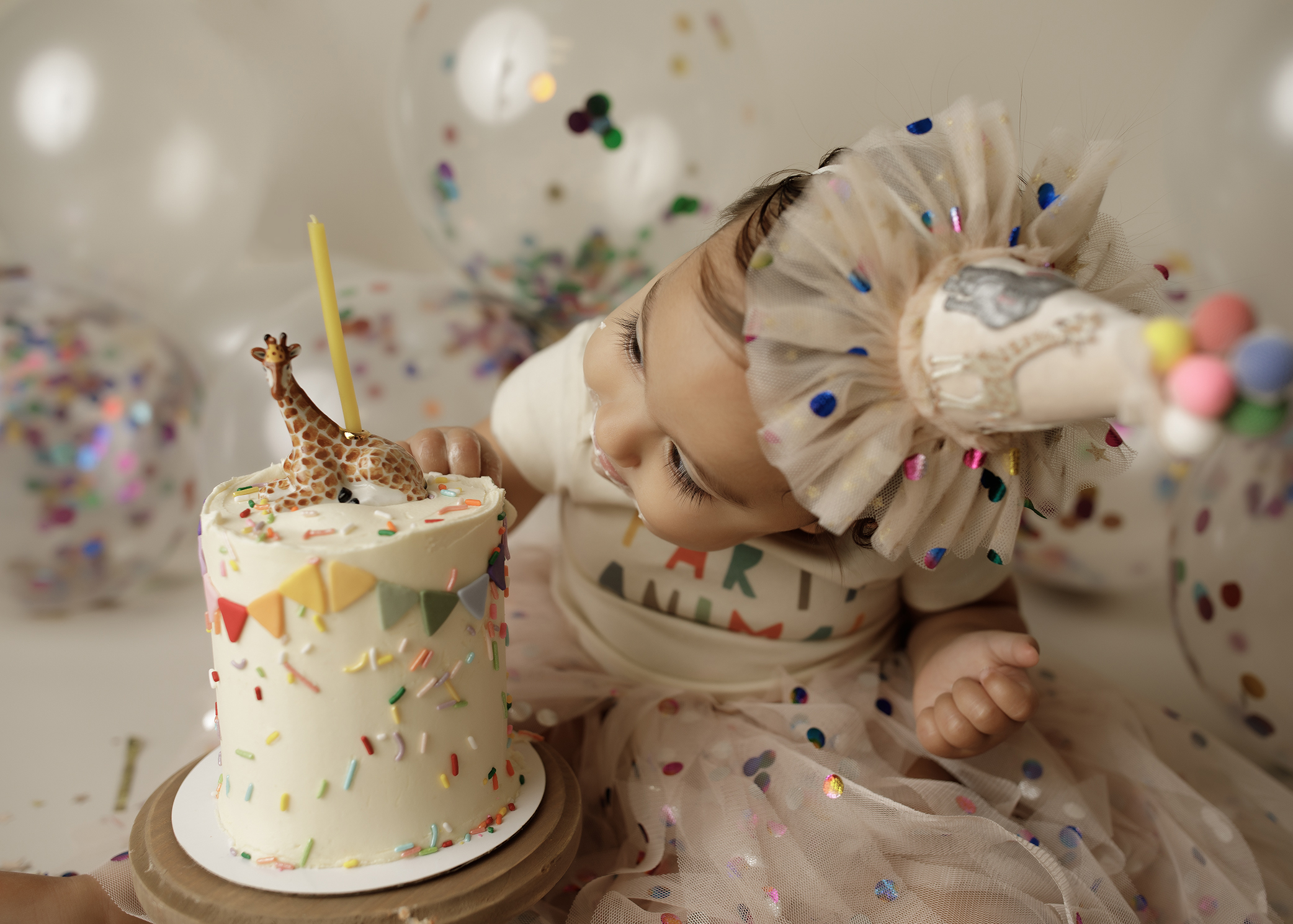 first birthday cake smash session with baby looking at cake